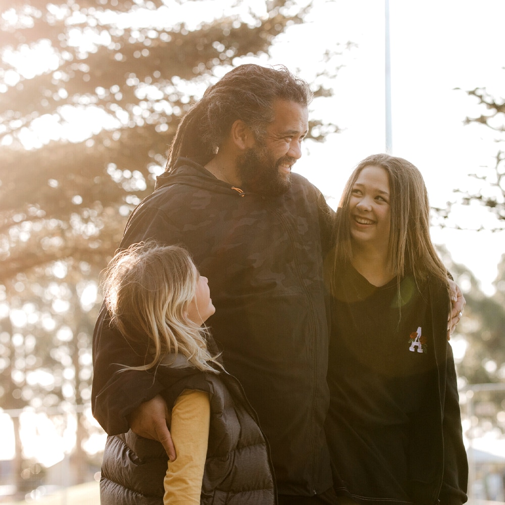 A father has his arms around his two daughters