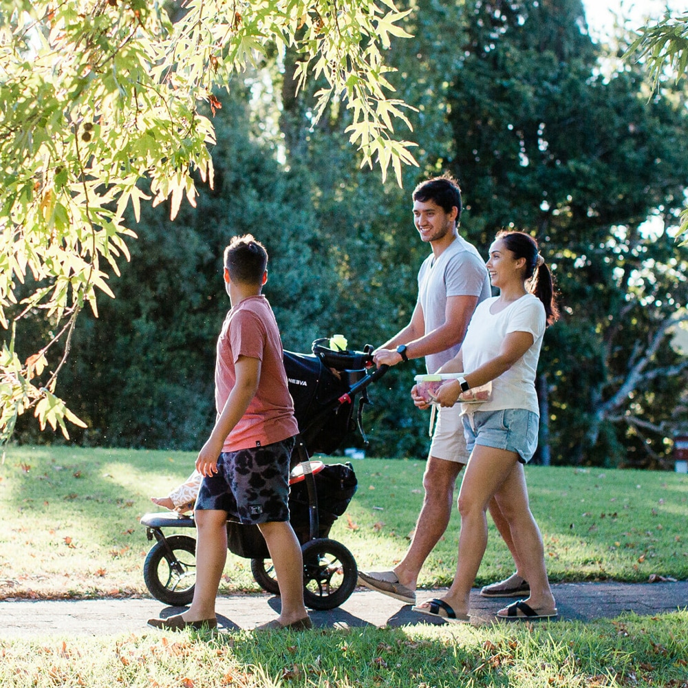 A family stroll through the park the father is pushing a stroller